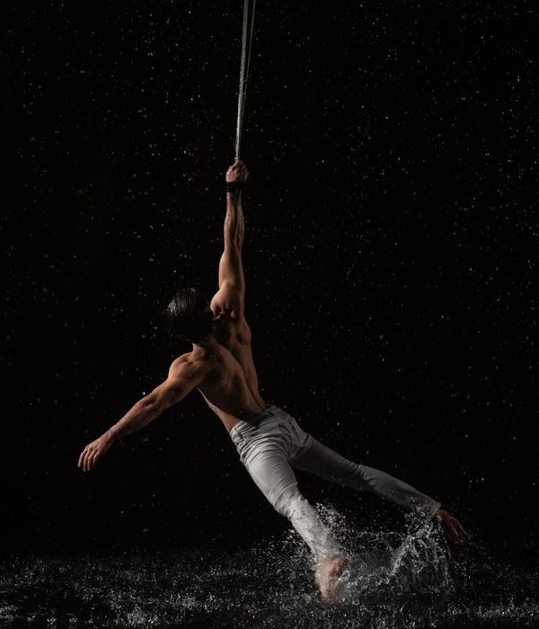 Man performing a controlled strength exercise in a minimalist dark studio.